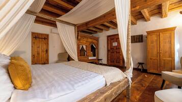 Una stanza con un letto di legno, tende bianche e un armadio in legno.