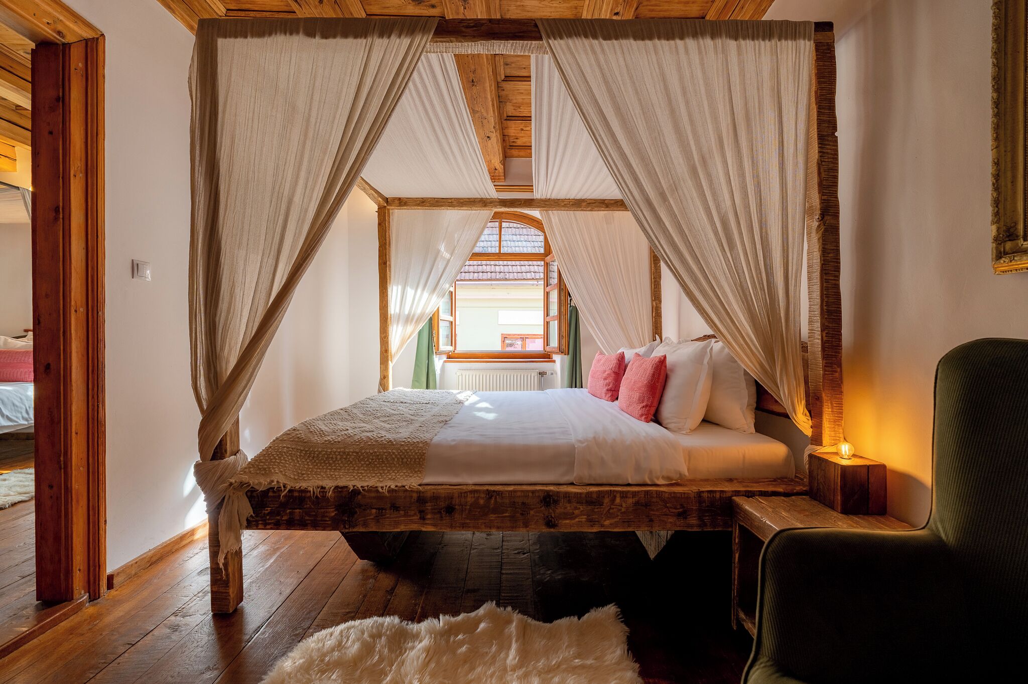 A rustic bedroom with a wooden bed, white bedding, and a canopy.