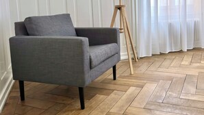 A grey armchair with a wooden floor lamp beside it. - Cozy & Fully Equipped 2-Bedroom Apartment in Central Zurich (Zürich)