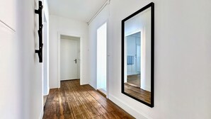 A hallway with wooden flooring, white walls, and a large mirror. - Cozy & Fully Equipped 2-Bedroom Apartment in Central Zurich (Zürich)