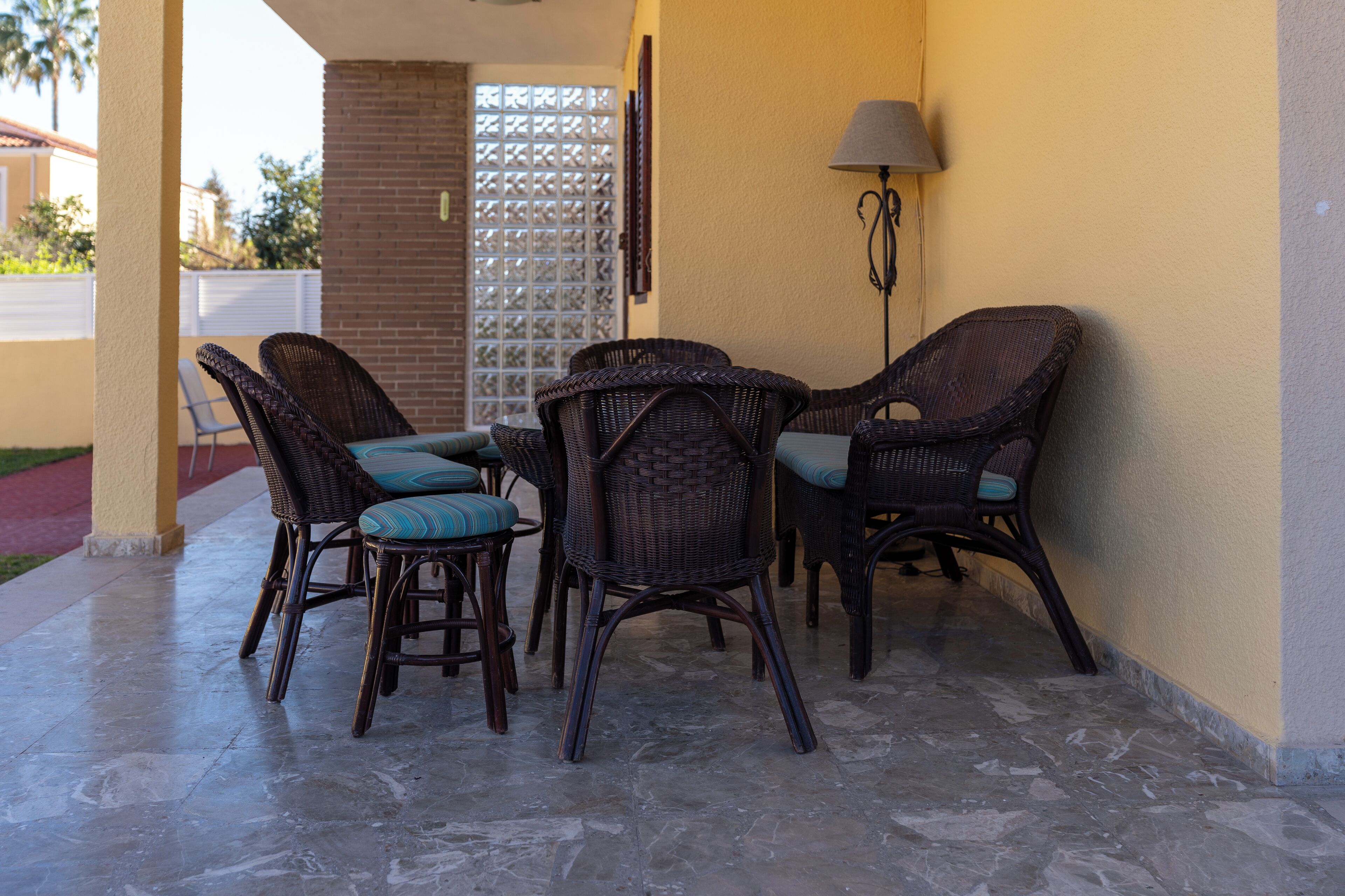 A covered patio area with wicker furniture and a lamp.