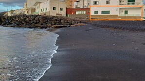Un edificio costero con muro de piedra, playa y costa rocosa.