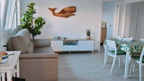 Una sala de estar moderna con un sofá, una mesa de comedor y una obra de arte colgada en la pared.