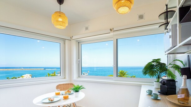 Una cocina moderna con ventanas amplias, un comedor y vistas al mar.