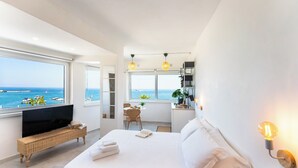 Un dormitorio moderno con una cama grande, televisor y vistas al mar.