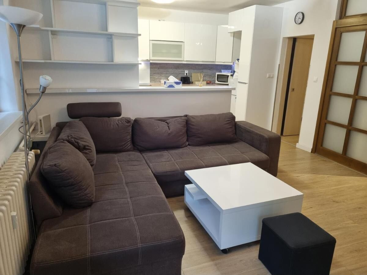 Ein modernes Wohnzimmer mit einem Ecksofa, einem weißen Couchtisch und einem schwarzen Hocker.