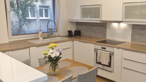 A modern kitchen with white cabinets, a wooden countertop, a built-in oven, and a window with a view of trees.