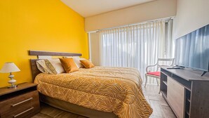 Una camera d'albergo con un letto, una scrivania, una sedia, una lampada e una televisione.