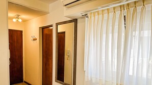 Camera d'albergo con tavolo in marmo, porte in legno, uno specchio e una finestra con tende leggere.