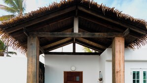 Un edificio bianco con una porta in legno e un ingresso con tetto di paglia.