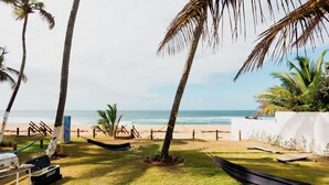 Vista sulla spiaggia con palme, un'amaca e una zona barbecue.