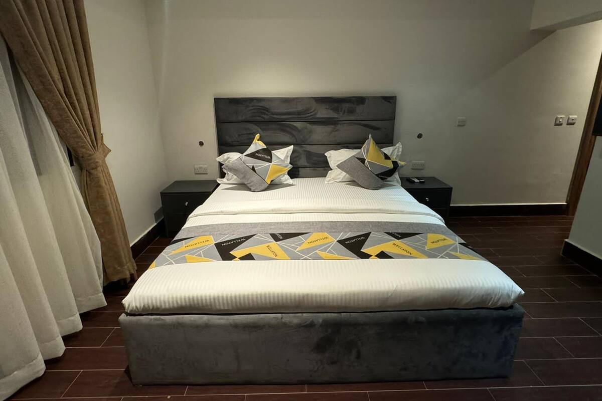A modern bedroom with a large bed, a headboard, and a bedside table.