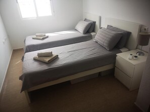 A twin bedroom with two beds, a nightstand with a lamp, and a window providing natural light. - Luxurious Villa La Vita e Bella Escape in Murcia (Murcia)