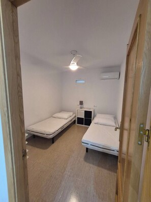 A small, clean room with two single beds, a ceiling fan, and a small table with a lamp. - Luxurious Villa La Vita e Bella Escape in Murcia (Murcia)