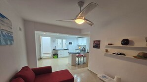 A modern living room with a red sofa, a ceiling fan, and a kitchen in the background. - Luxurious Villa La Vita e Bella Escape in Murcia (Murcia)