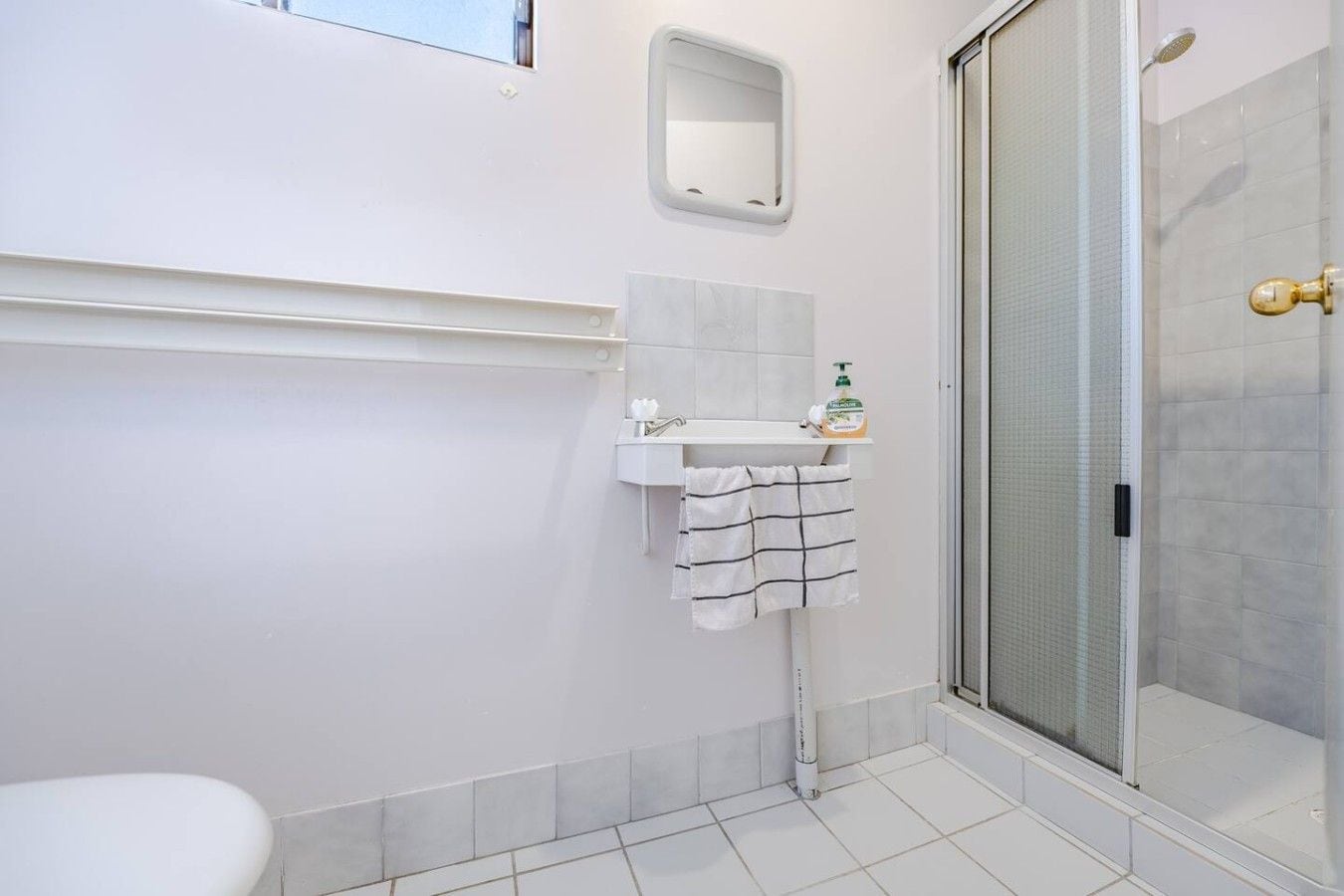 A bathroom with a shower, a sink, and a mirror.