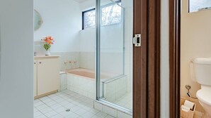 Une salle de bain avec une douche à parois de verre, des toilettes et un lavabo agrémenté d’un vase de fleurs.