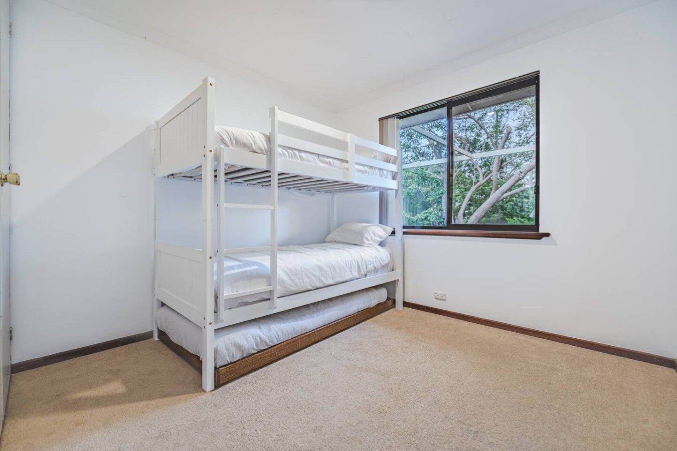 Ein Stockbett in einem Zimmer mit Fenster und Tür.