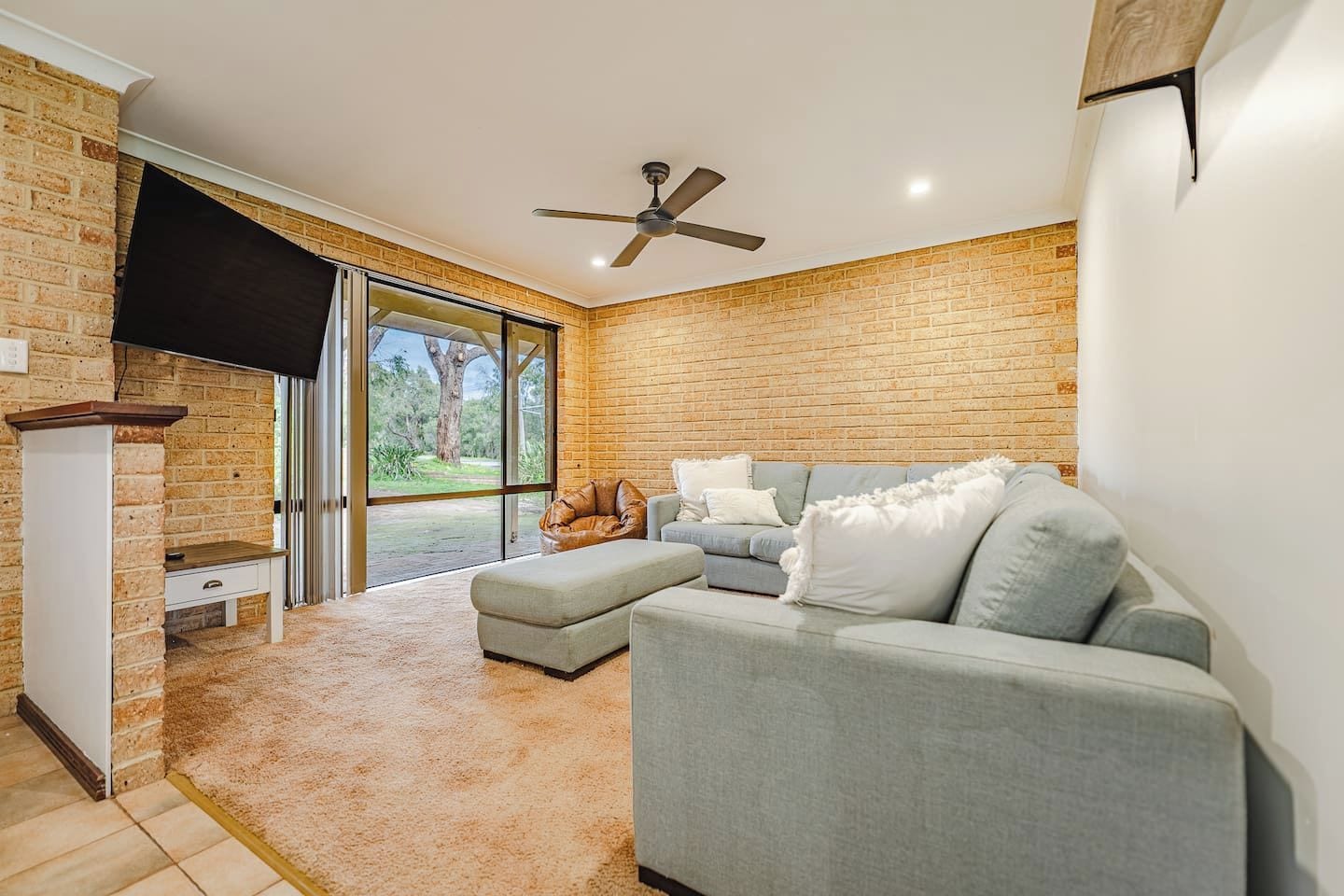 A modern living room with a grey sectional sofa, a small table, and a ceiling fan.