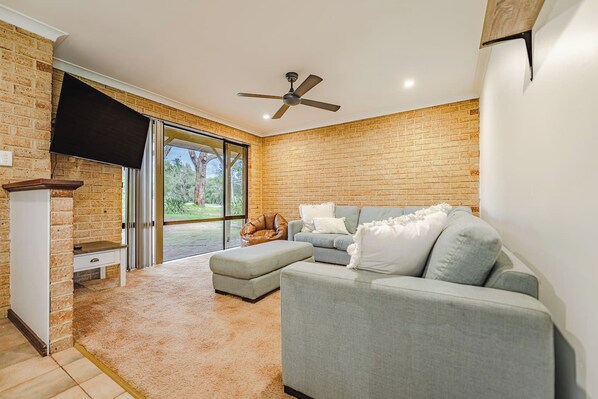 A modern living room with a grey sectional sofa, a small table, and a ceiling fan.