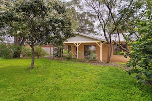 A house with a covered porch, a lawn, and trees.