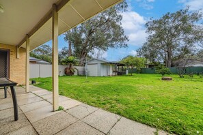 A backyard with a patio, a covered area, and a fenced yard.