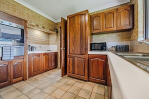 A kitchen with wooden cabinets, a microwave, and a tiled backsplash.
