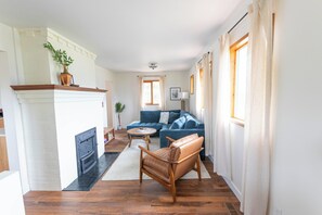 Un salon avec une cheminée, un canapé bleu, une chaise en bois et une table à manger.