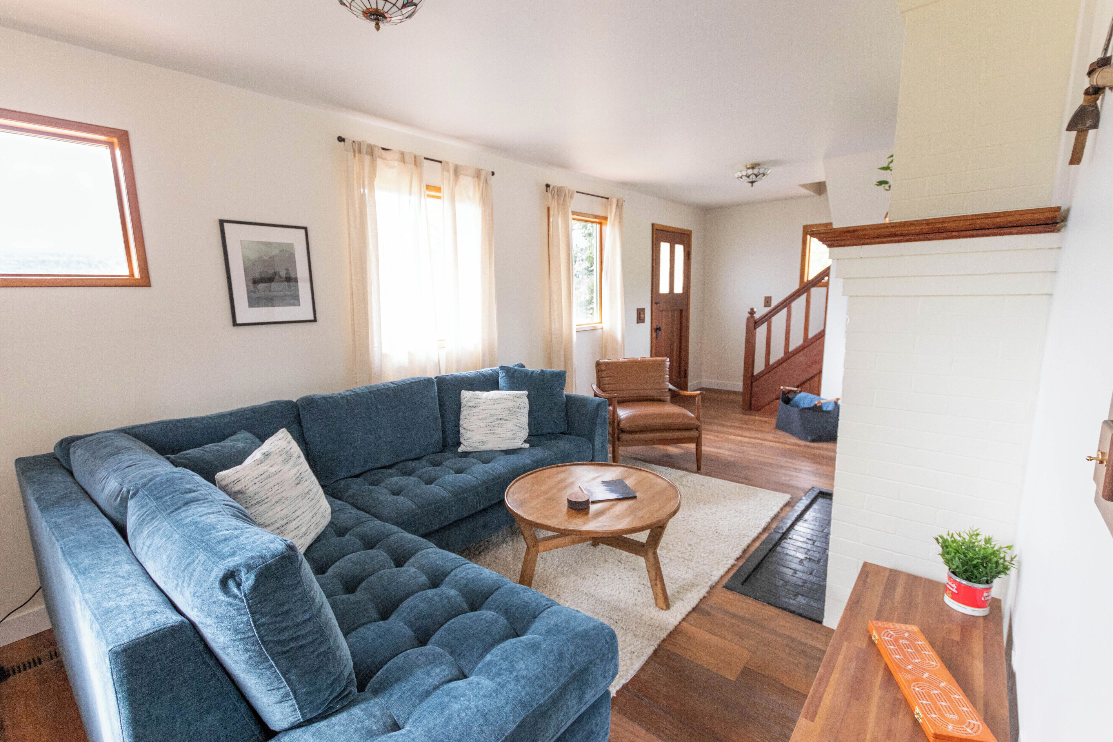 A living room with a sectional sofa, a coffee table, and a staircase leading to an upper level.