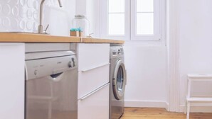 A compact kitchen with a washing machine, a dishwasher, and a window with white frames. - Chic & Luxurious 2-BR Escape Designed for Elegance (Gibraltar)