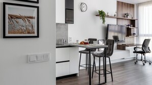 A modern kitchen with a dining area, a flat-screen TV, and a large window. - Stylish studio near the National Library (Minsk)