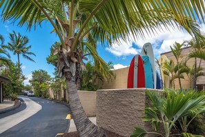 A street with palm trees, a curved road, and a building with a surfboard sign.