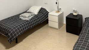 A bedroom with two single beds, a nightstand, a bedside table, a lamp, and a framed picture of a bull on the wall.