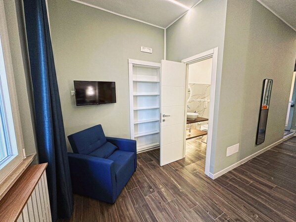 A modern living room with a blue sofa, a television mounted on the wall, and a partially open door leading to a bathroom. - Central Vasto Histonium (Vasto)