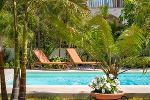 A pool area with lounge chairs and lush greenery. - Villa Bali With Pool by Wonderful Italy (Syracuse)