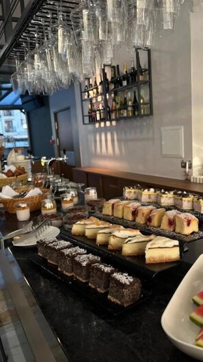 Ein Dessertbuffet mit verschiedenen Kuchen und Gebäck, eine Weinstauraum und hängende Gläser.