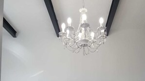 A bedroom with a tufted headboard, two patterned pillows, a bedspread, and a chandelier. - CASAPANCHO 3 (CN)