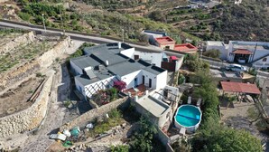 An aerial view of a residential area with a house featuring a swimming pool, a stone retaining wall, and a paved driveway. - CASAPANCHO 3 (CN)