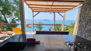 A kitchen with a view of the sea, a gas stove, and a sink.