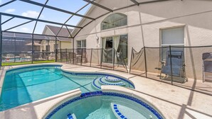 A swimming pool with a glass enclosure, a covered patio area, and a view of the surrounding neighborhood. - 5BR Family Fun Home | Game Room & Private Pool (Kissimmee)