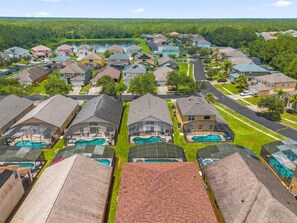 A residential area with houses, a swimming pool, and a lake in the background. - 5BR Family Fun Home | Game Room & Private Pool (Kissimmee)