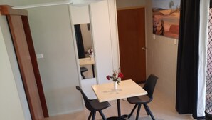 A small, clean room with a bed, a table with chairs, a ceiling fan, and a painting on the wall. - Three Falls Holiday Millaa Millaa waterfall circuit. Famous Millaa Milllaa Fall  (Millaa Millaa)