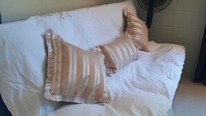 A bed with white bedding and striped pillows, a standing fan, and a wall with a decorative painting. - Three Falls Holiday Millaa Millaa waterfall circuit. Famous Millaa Milllaa Fall  (Millaa Millaa)