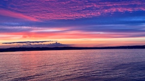 A sunset over a calm body of water with a distant shoreline silhouette. - Torquay, 1 Bedroom, Sleeps 4, Free Parking, Torbay (Torquay)