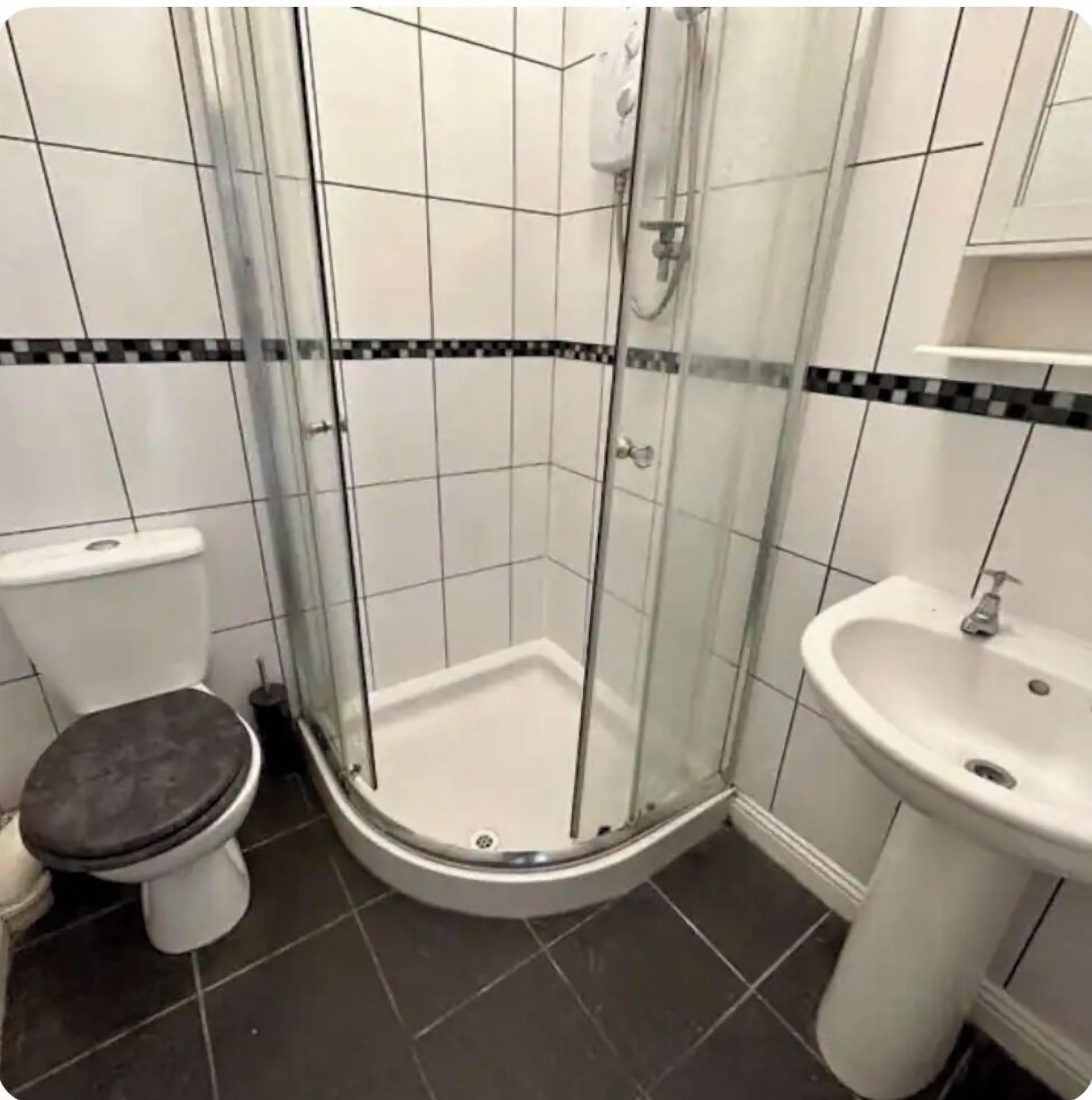 A bathroom with a glass-enclosed shower, a toilet, and a sink.