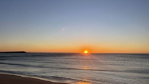 Uma praia com o pôr do sol no oceano.