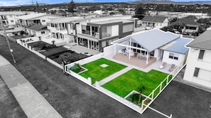 Un edificio residencial moderno con techo plano, patio cubierto y césped bien cuidado.