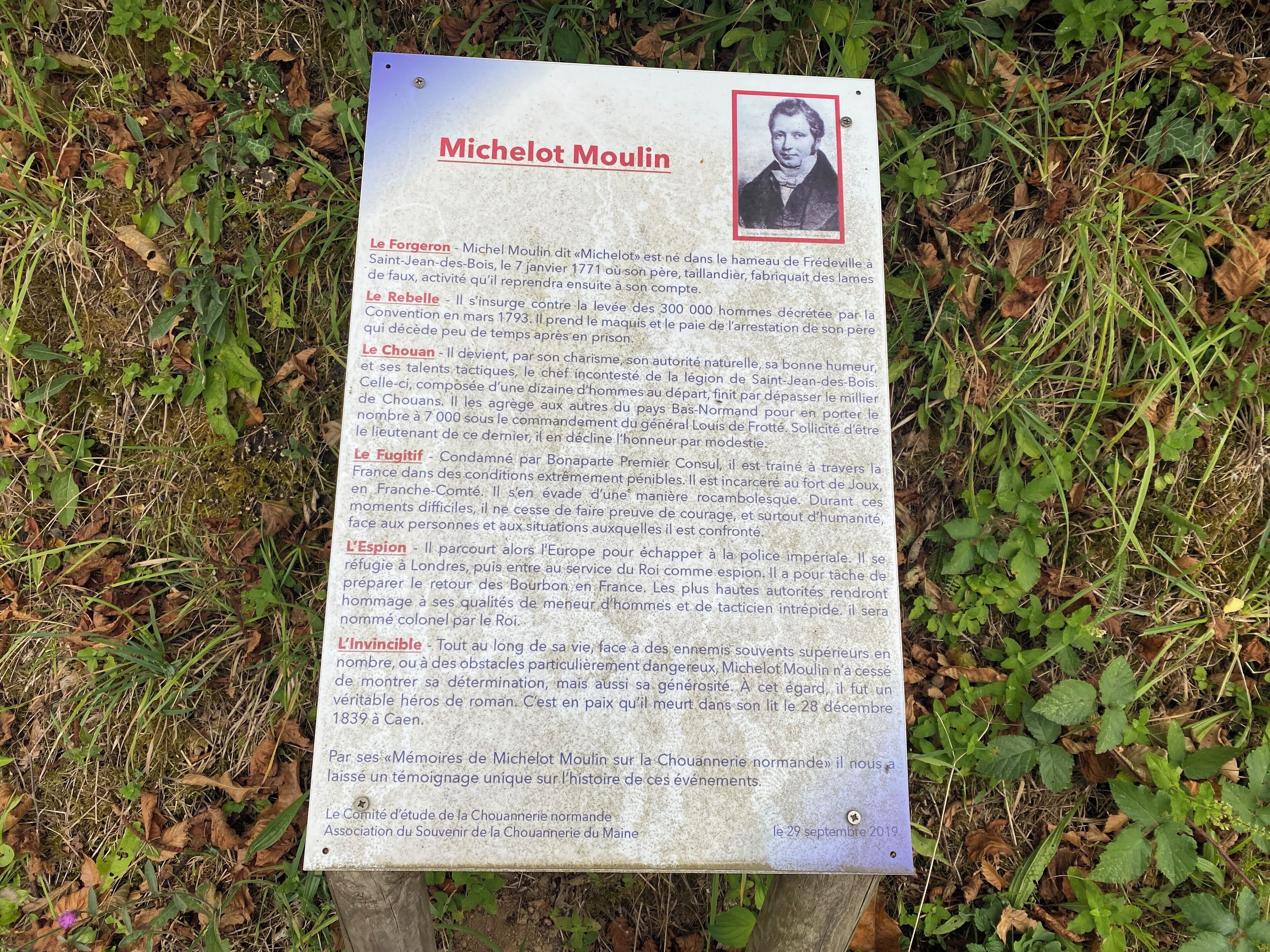 Una placa conmemorativa histórica que detalla la vida de Michelot Moulin, incluyendo sus roles en diversas campañas militares.