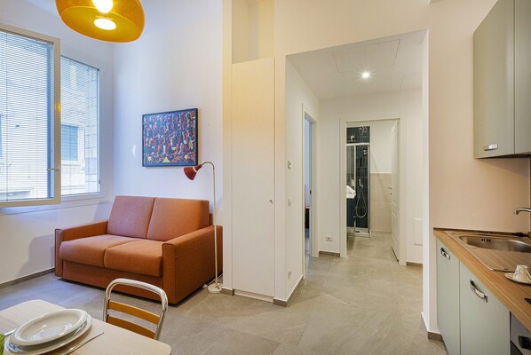 A modern living room with a sofa, a dining table with plates, and a painting on the wall. - Carignano Sweet Home by Wonderful Italy (Genoa)