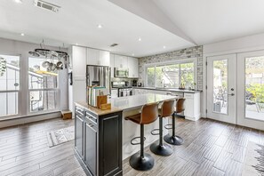 A modern kitchen with a large island, bar stools, and a view of the outdoors.